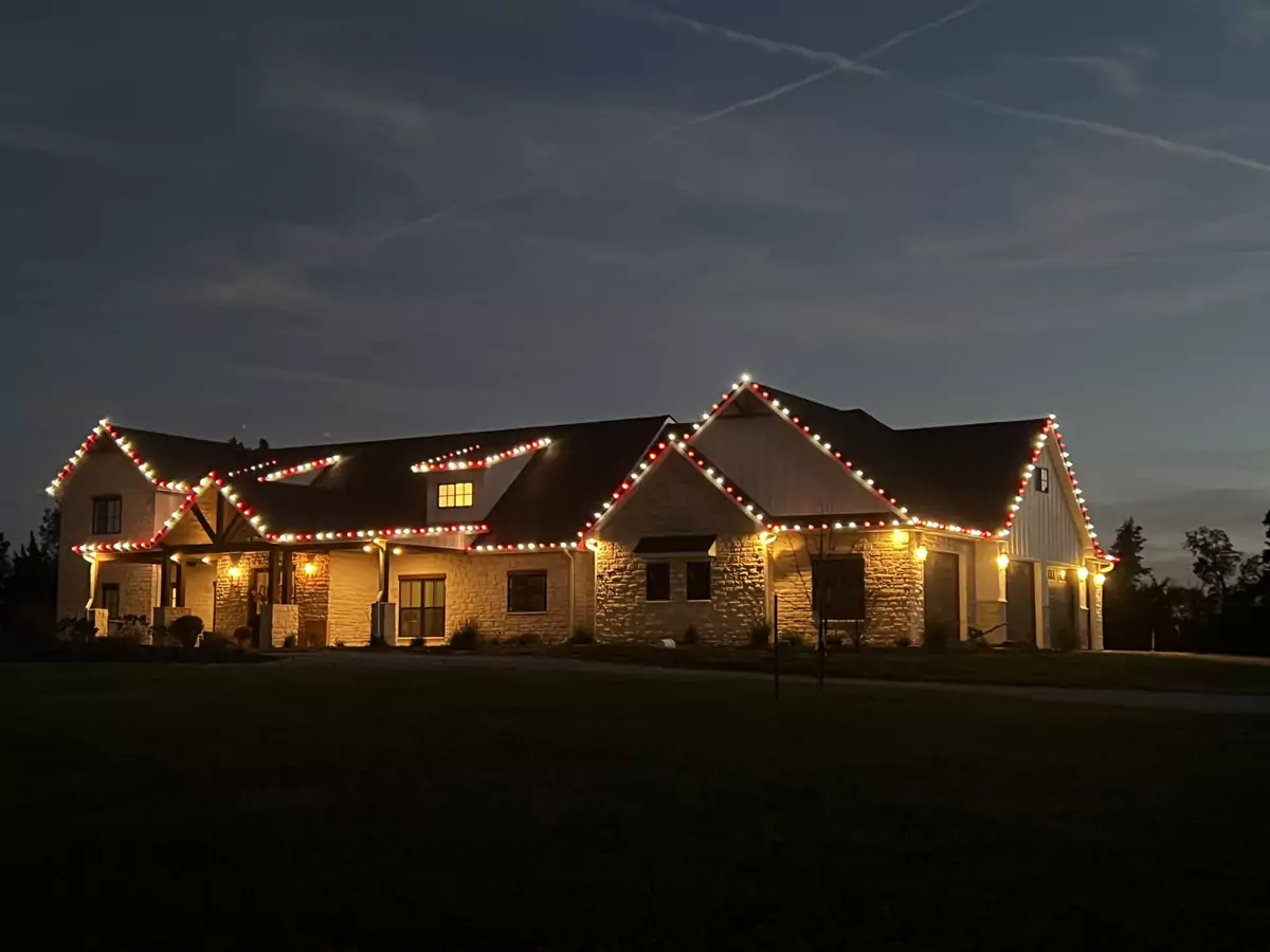 Modern farmhouse at dusk with red and white C9 lights on every gable